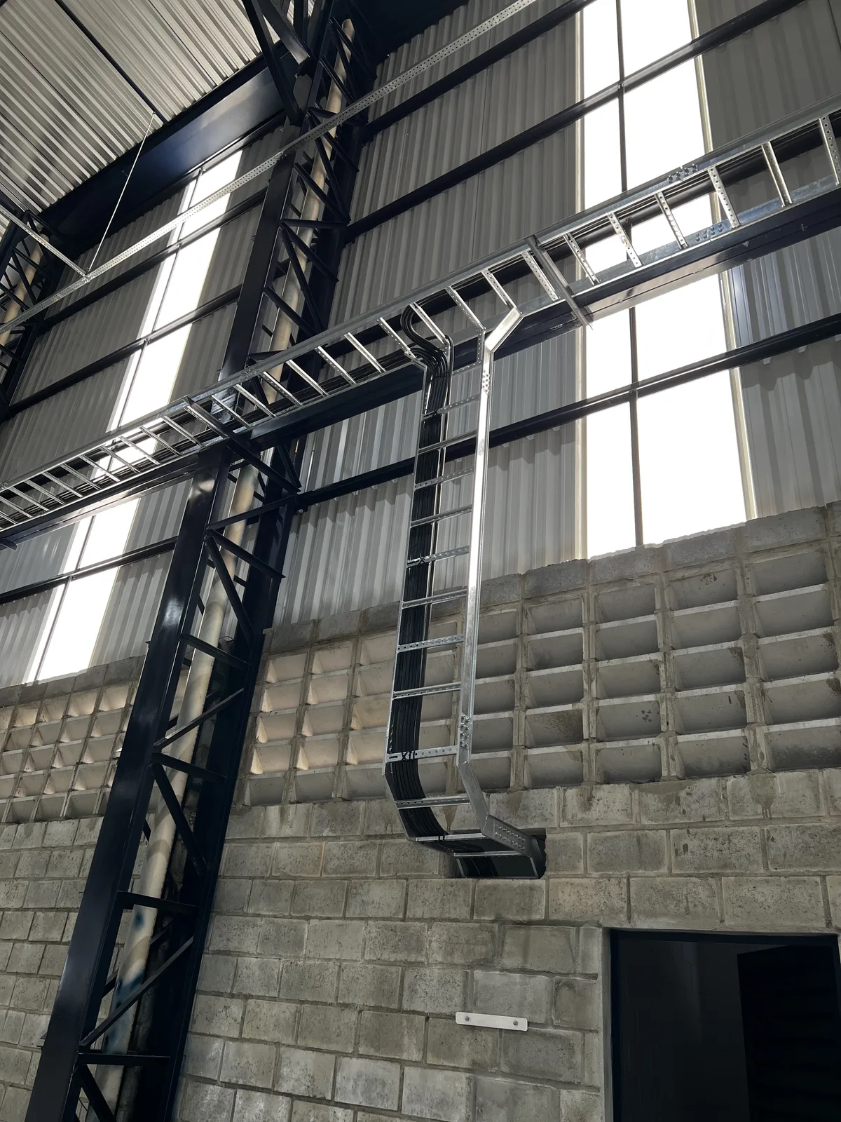 Eletrocalha e escada de cabos instaladas em estrutura metálica de galpão industrial