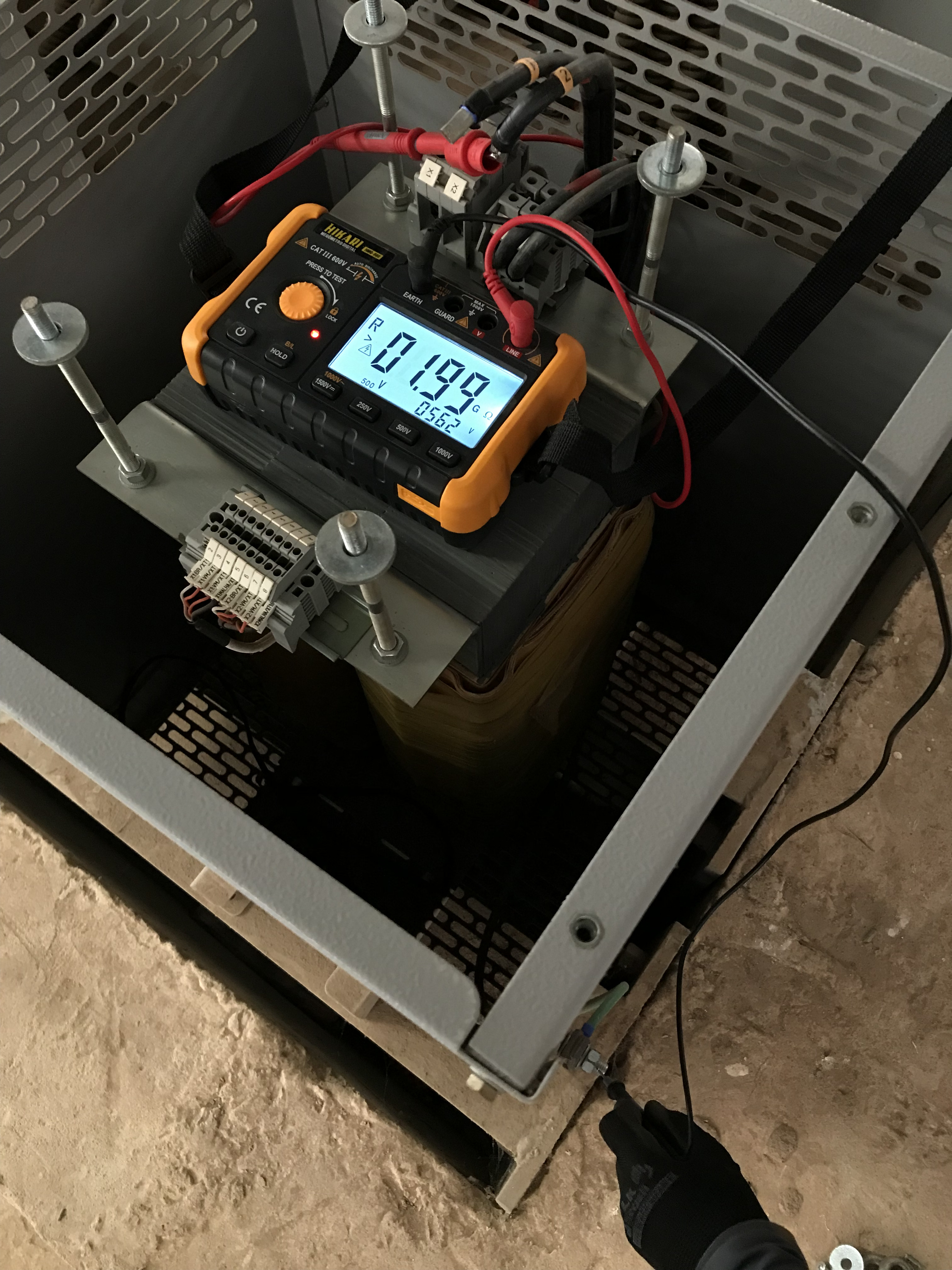 Técnico realizando ensaio de resistência de isolamento com megômetro em transformador de painel elétrico