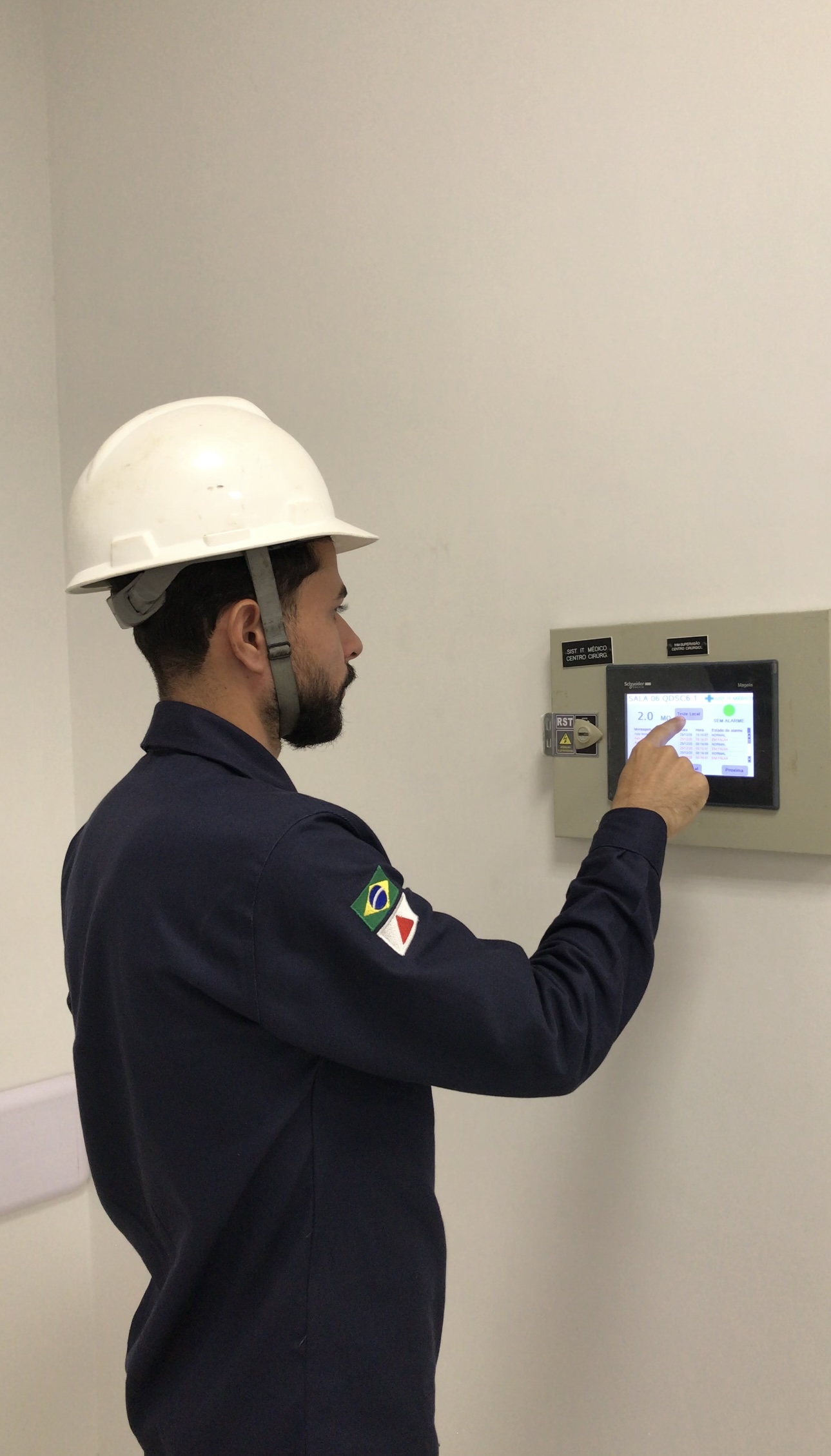Técnico verificando painel de supervisão do Sistema IT Médico em corredor hospitalar