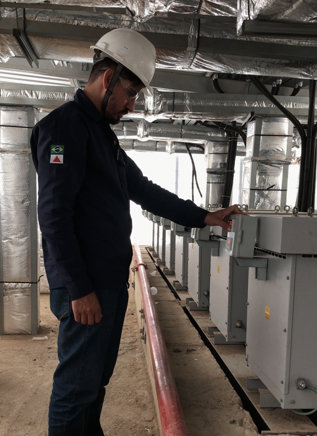 Técnico com equipamento de proteção inspecionando cubículos de média tensão em subestação
