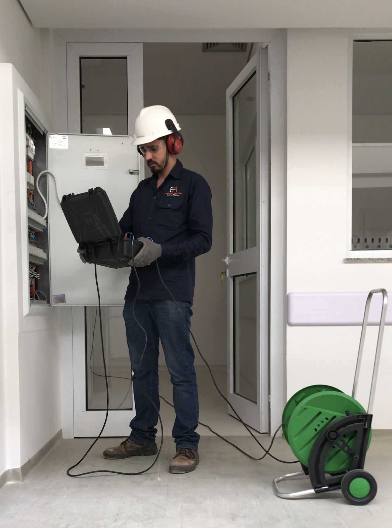 Técnico da Engenharia Alcântara realizando ensaio elétrico com equipamento portátil em quadro de distribuição