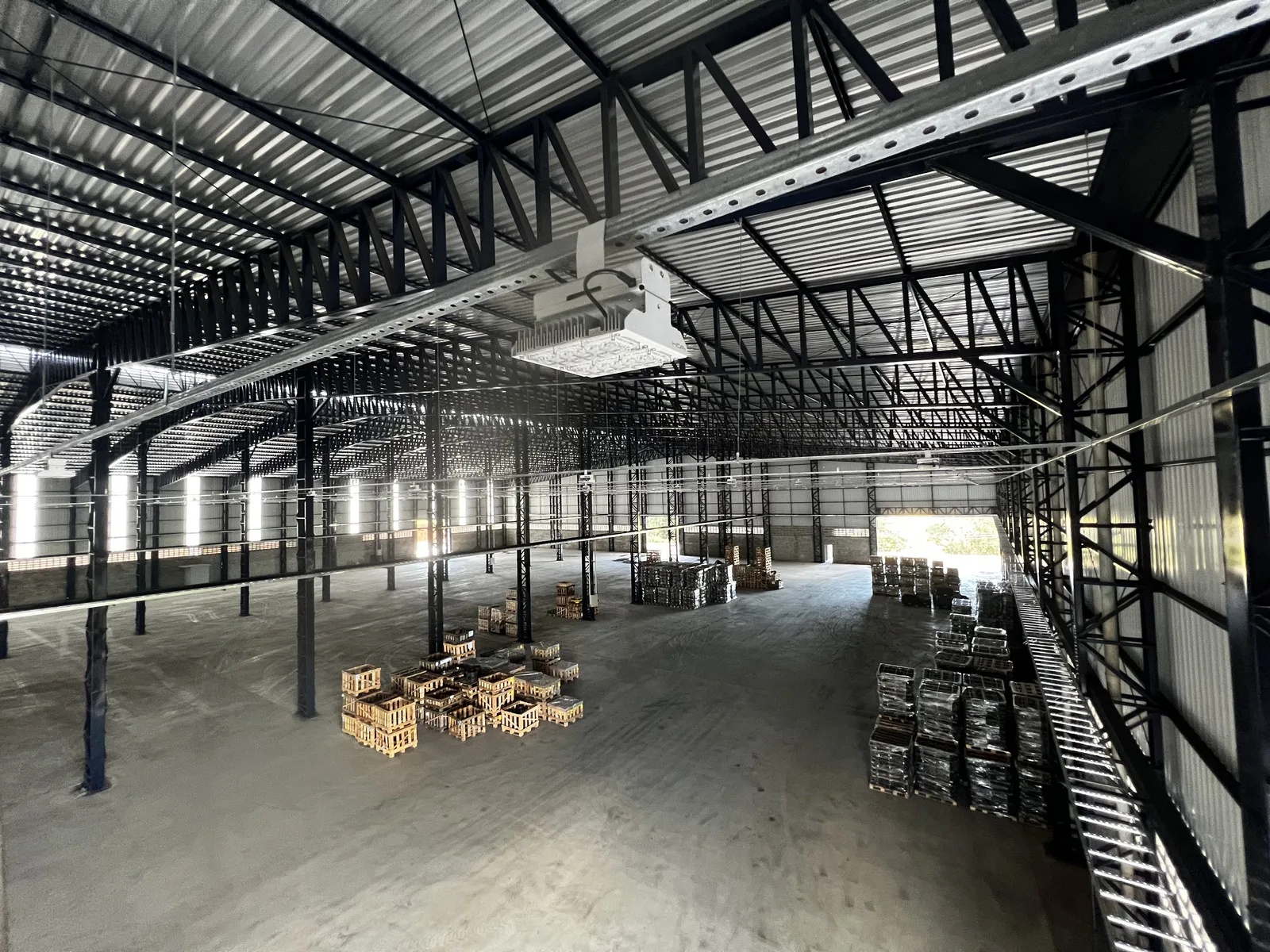 Luminária industrial LED instalada em estrutura metálica de galpão