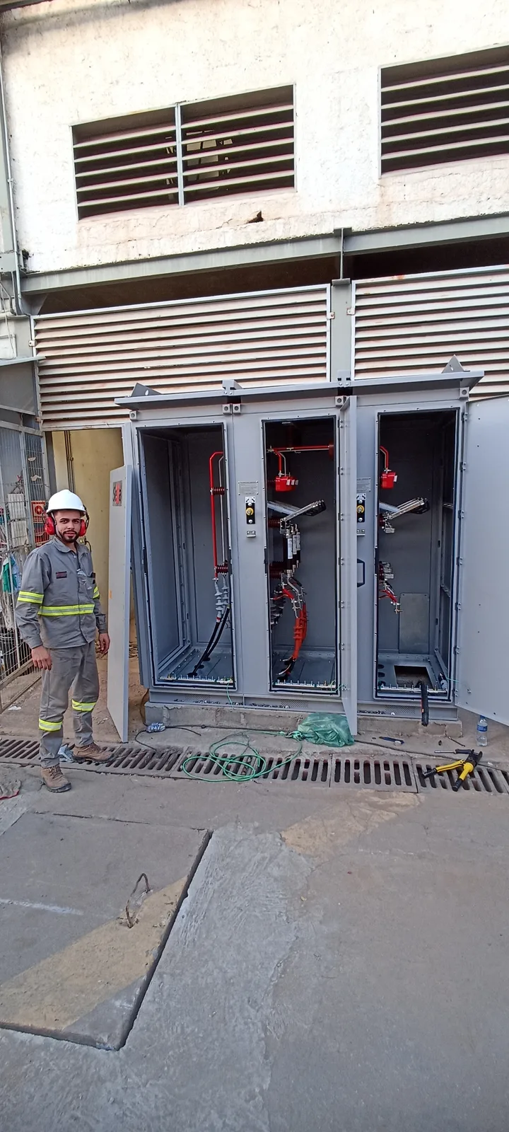 Técnico com EPI ao lado de cubículos de média tensão instalados