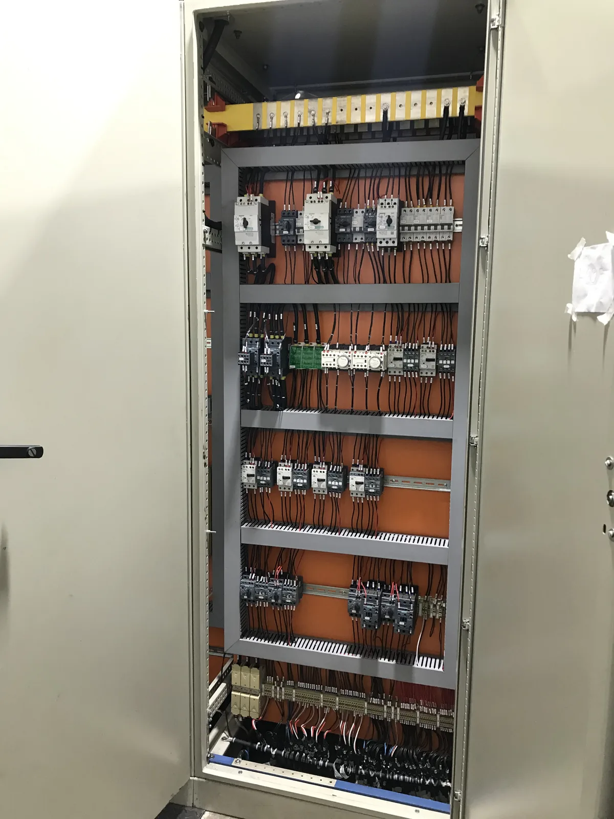 Interior de painel elétrico industrial com contatores, disjuntores e cabeamento organizado
