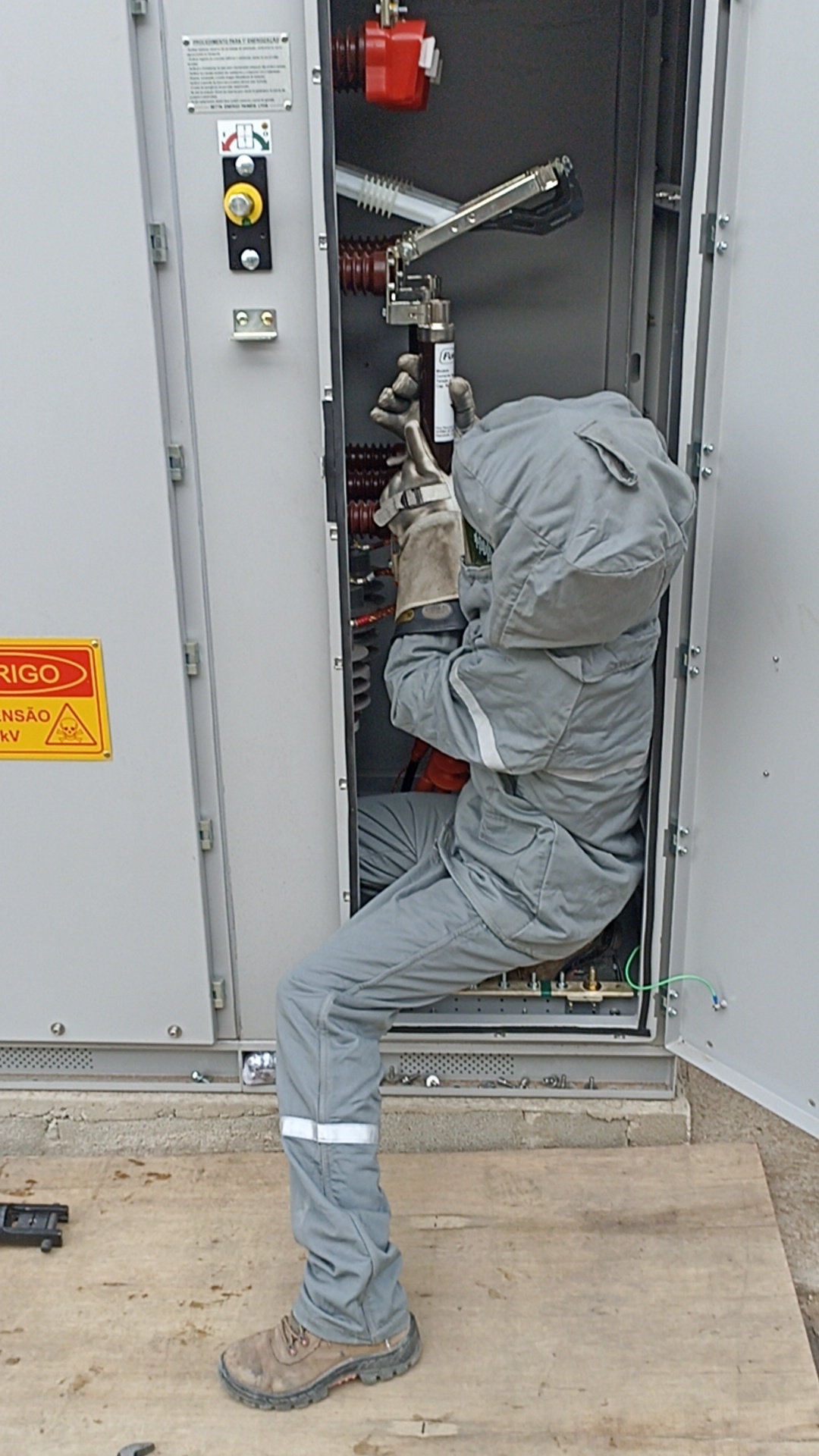 Técnico com EPI realizando ensaio técnico em painel elétrico